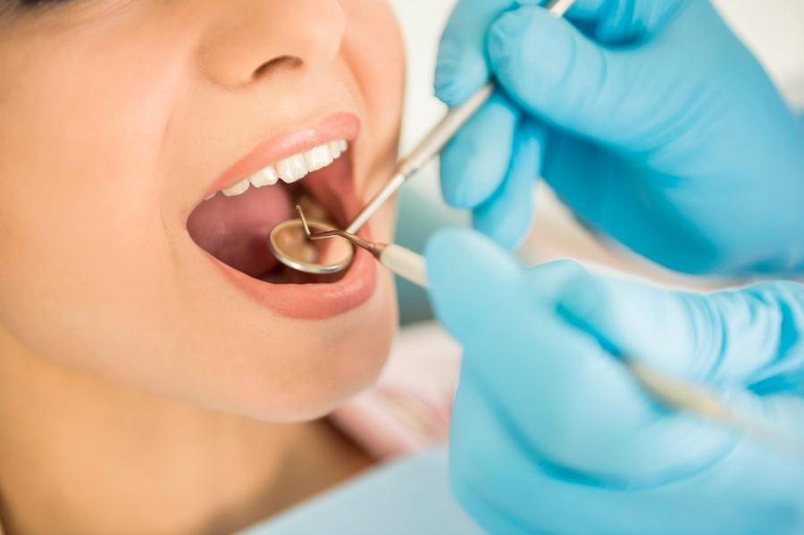 Przegląd zębów pacjentki narzędziami stomatologicznymi 